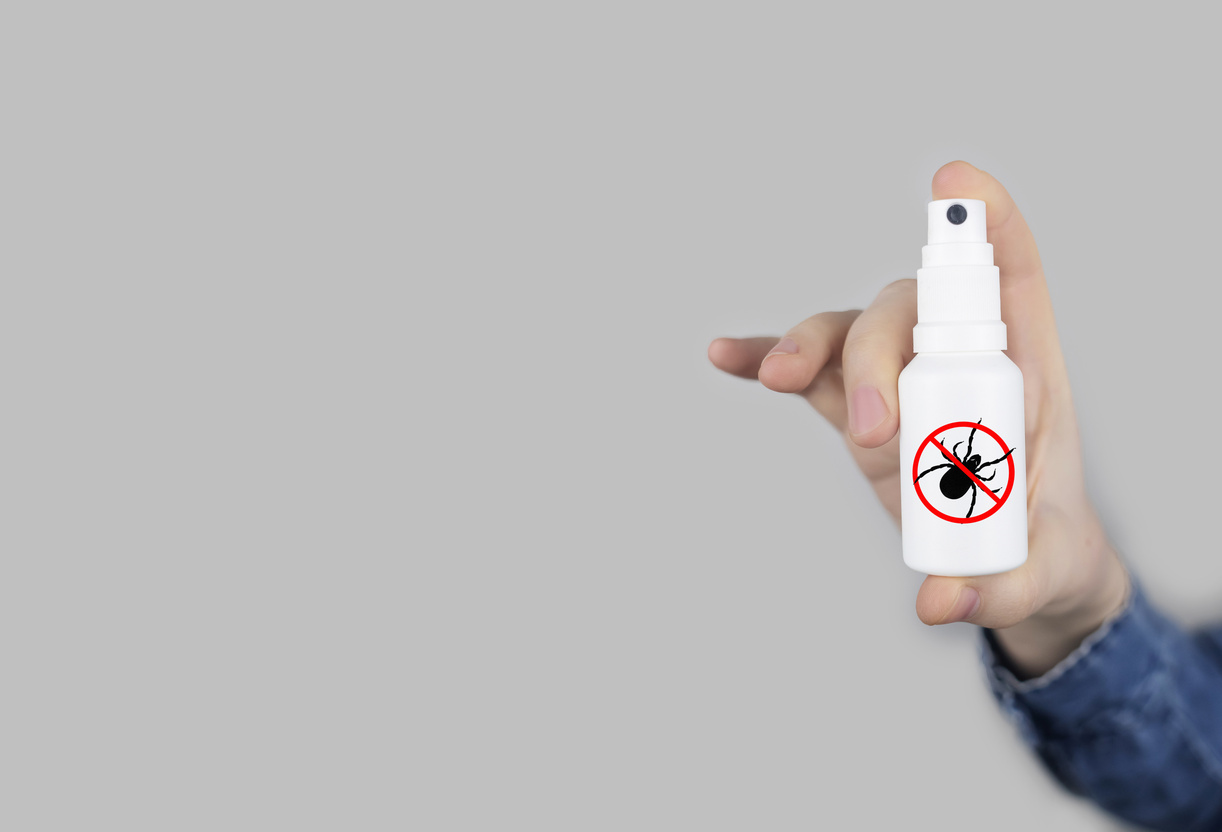 Tick repellant. Insect protection. Girl holds a spray on a white background that will protect against ticks. Repelling blood-sucking insects.